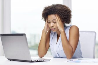 education, business, fail and technology concept - african american businesswoman or student with laptop computer and papers at office